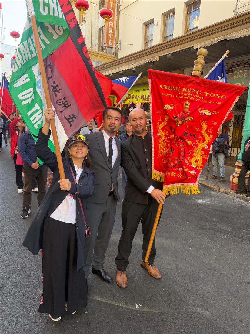 Participants standing with Chee Kung Tong flags and the embroidered red lodge banner