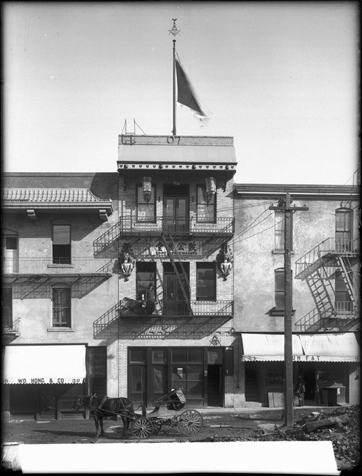 The original Chee Kung Tong San Francisco chapter building, with balconies, an exterior stairway and a horse-drawn cart.